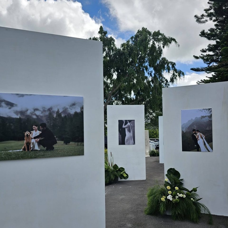 An outdoor gallery walkway of white plinths displaying framed wedding portraits at Hillside Kokol