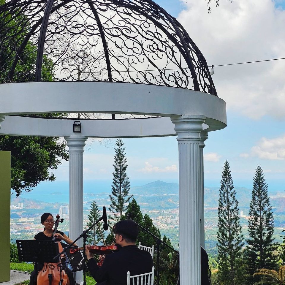 A string duo playing under the white iron gazebo at Hillside Kokol, overlooking the valley and sea